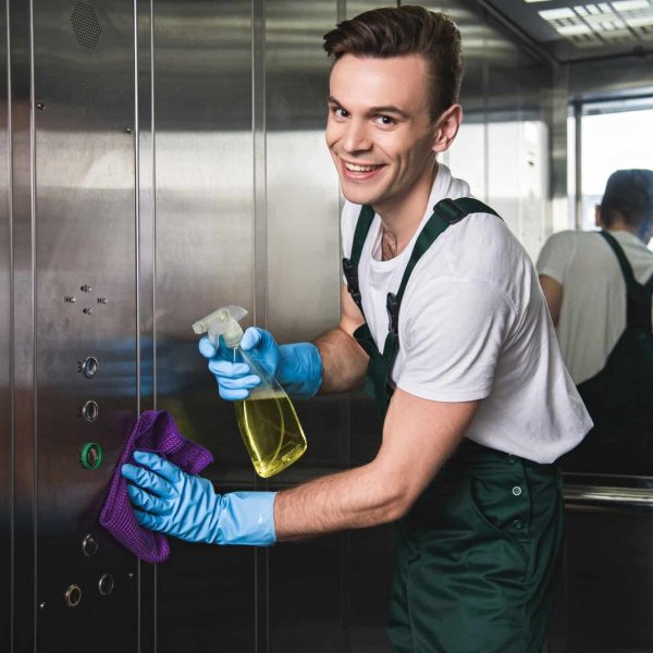 young-cleaning-company-worker-cleaning-elevator-and-smiling-at-camera.jpg